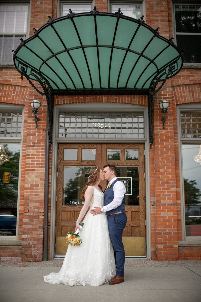 bride and groom kissing in front of hotel in chatham