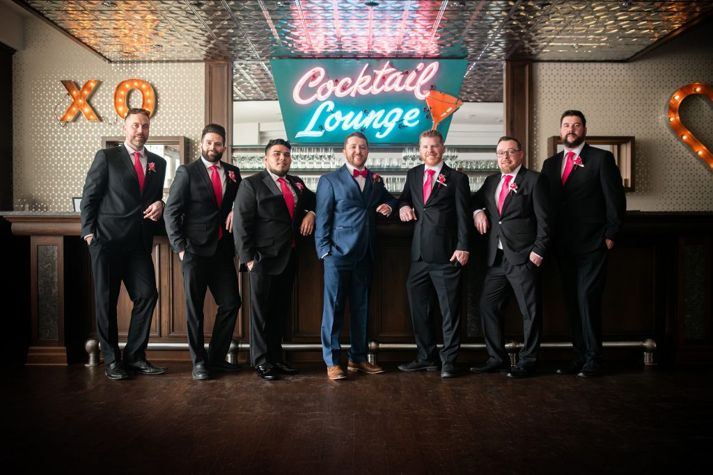 groom with his groomsmen standing by the cocktail lounge bar at the retrosuites hotel in chatham