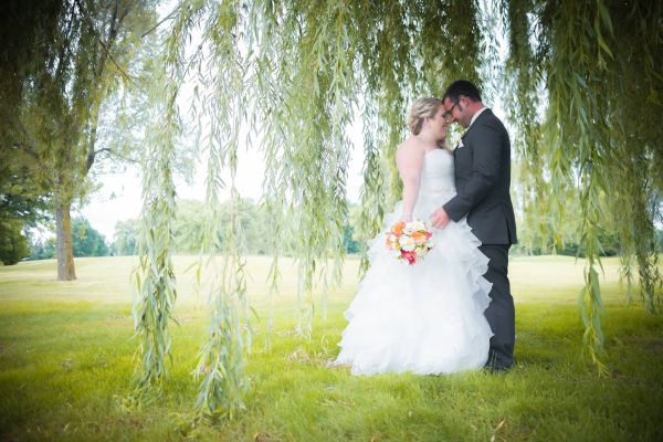 bride and groom standing under willow tree
