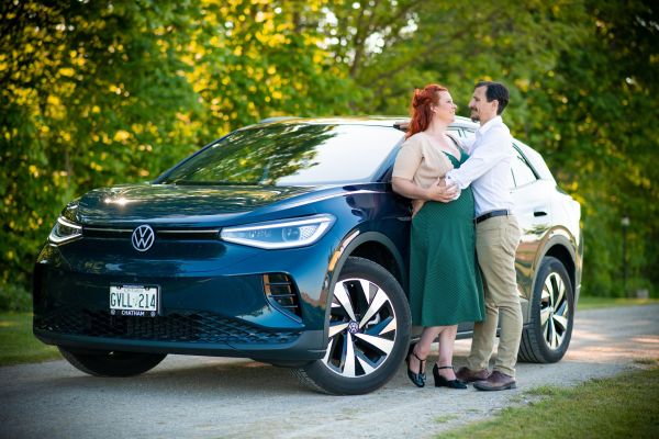 Engaged couple standing together and outside of their new vehicle