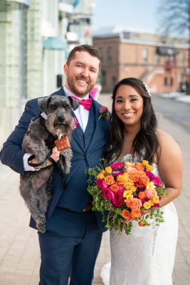 bride and groom holding their pet dog and wedding flowers (in chatham)
